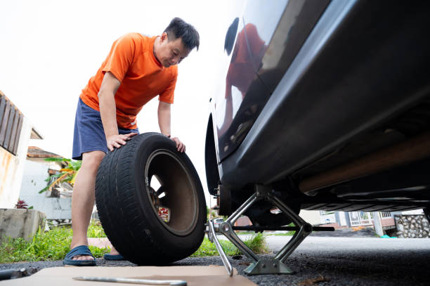 Man changing a car tire, with the vehicle securely supported by jack stands.