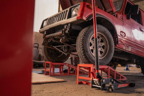 Red Jeep lifted by a floor jack and sturdy red Jack Stands for maintenance.