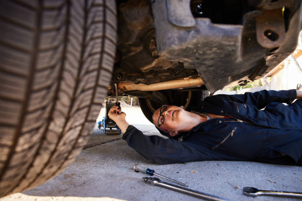 Woman mechanics under car, safely supported by jack stands.