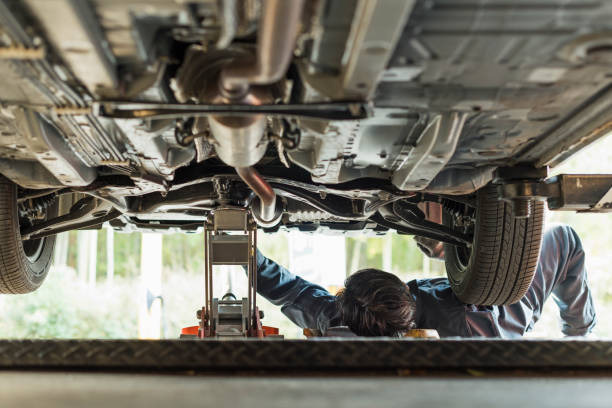 Mechanic working under a car securely lifted with jack stands.