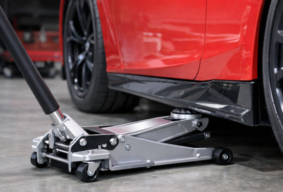 A silver hydraulic floor jack lifts a red car. Always use Jack Stands for safety.