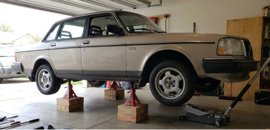 Vintage car lifted securely on red jack stands placed on wood blocks.