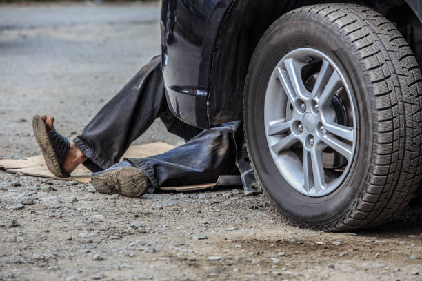 Person working unsafely under a car, highlighting the need for proper Jack Stands for safety.