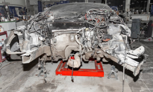 Stripped car chassis resting on jack stands for repair in a workshop.