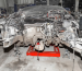 Stripped car chassis resting on jack stands for repair in a workshop.