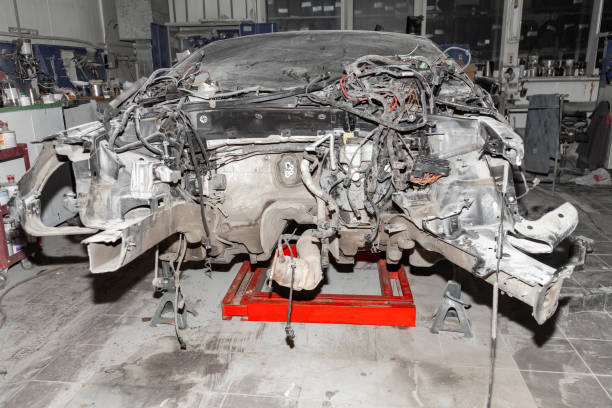 Stripped car chassis resting on jack stands for repair in a workshop.