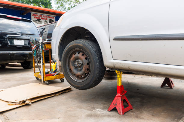 Silver car lifted by red jack stands for tire service in a garage.