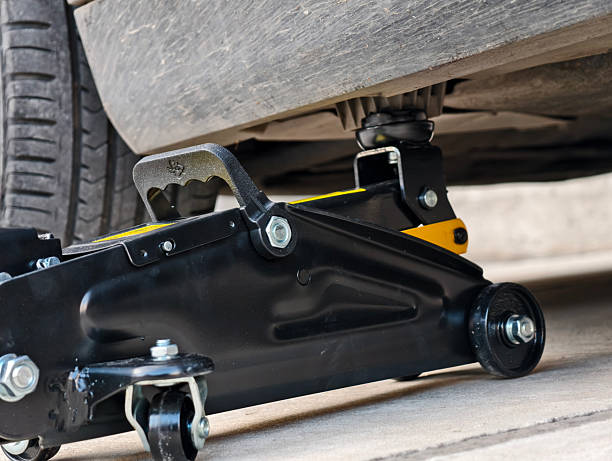 Hydraulic floor jack lifting a car, requiring secure Jack Stands for safety.