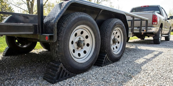 Dual axle trailer securely chocked on gravel, often supported by jack stands for maintenance.