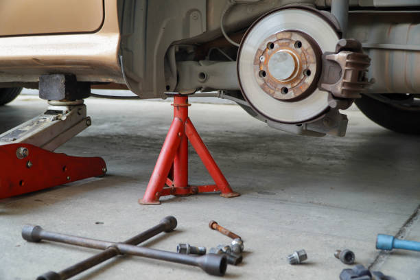 Car lifted on red Jack Stands and floor jack for brake work, tools nearby.