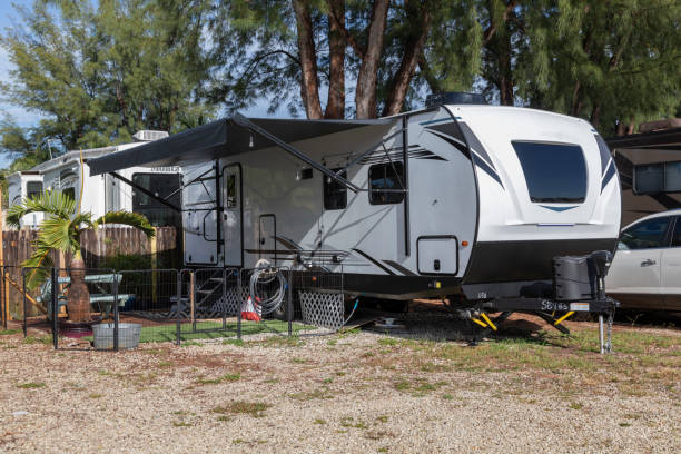 Modern travel trailer with awning deployed in an RV park. Always use jack stands for leveling.