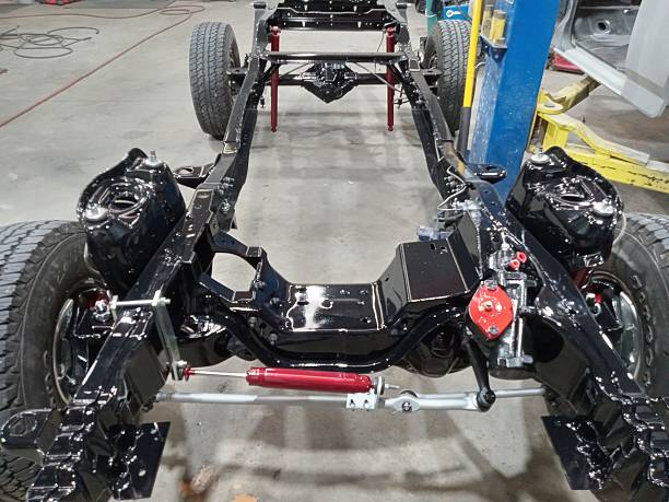 Full view of a restored black truck chassis with new wheels and suspension.