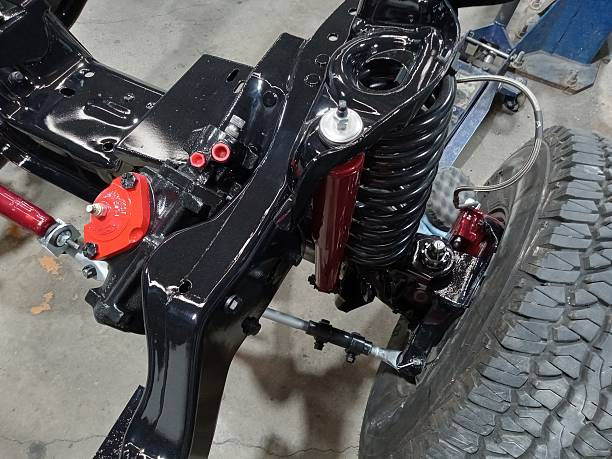Detailed view of the shiny black truck frame's new front coil spring suspension.